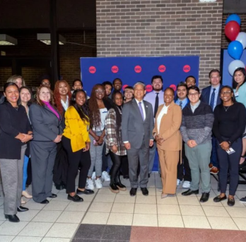 A group of people pose in front of a red and blue UIC backdrop. 